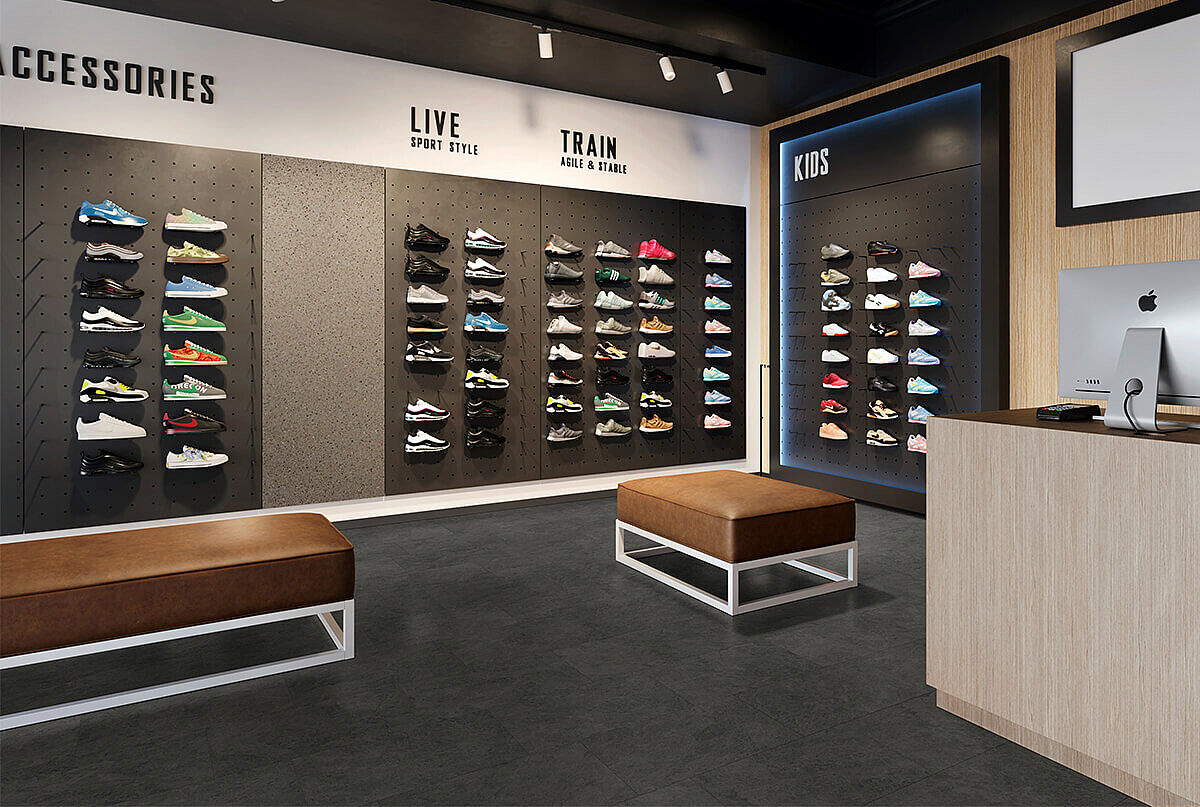 Sneaker store with shoe walls, benches and checkout area on recycled elastic flooring in a dark stone look with subtle mottled texture.