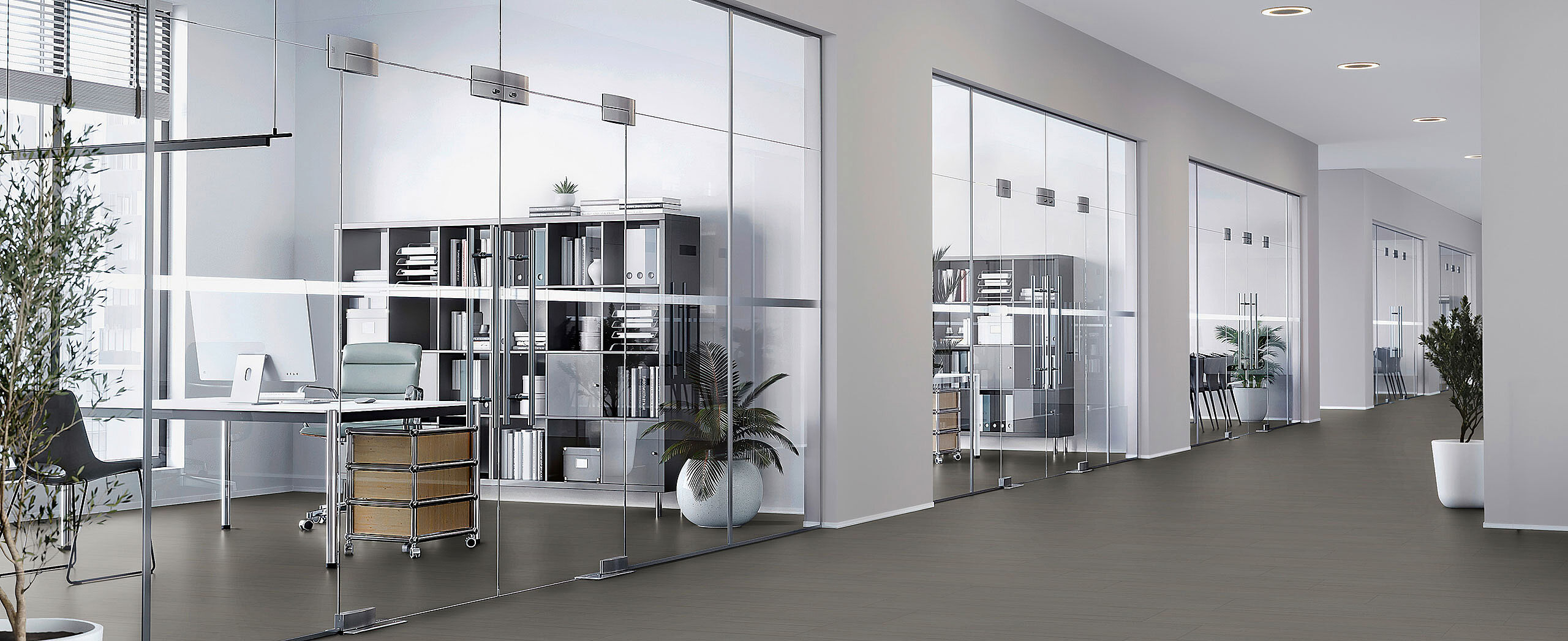 Modern office with glass walls and workstations, recycled elastic flooring in a dark grey finish with a calm matte surface.